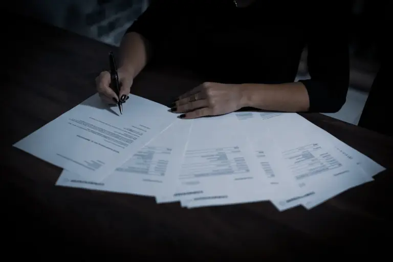A person signing legal documents as part of an estate planning process
