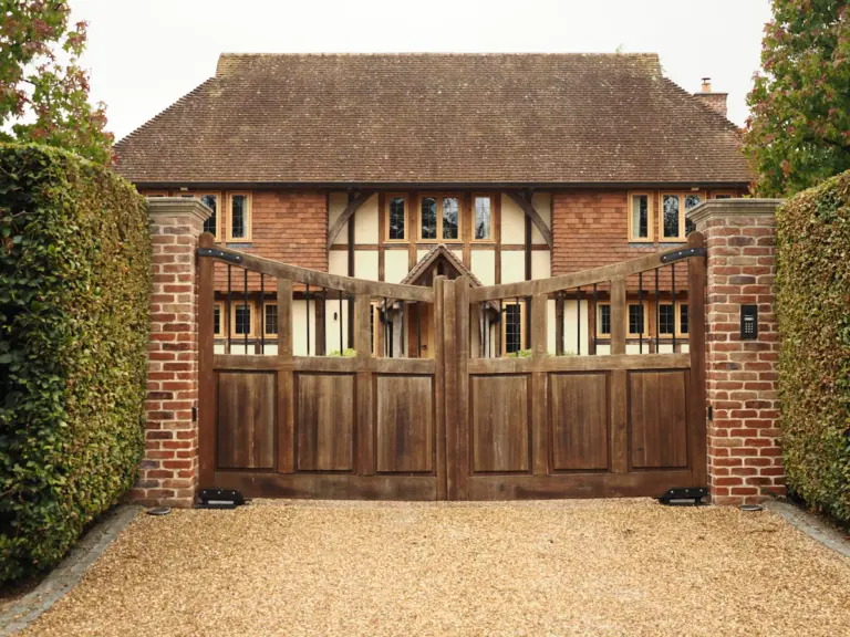 A large wooden driveway gate at the entrance to a residential property