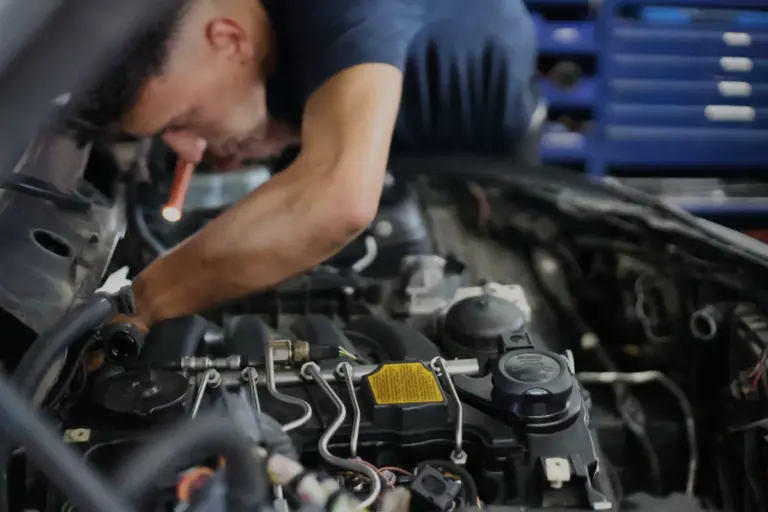 Automotive mechanic inspecting a car engine in a repair workshop